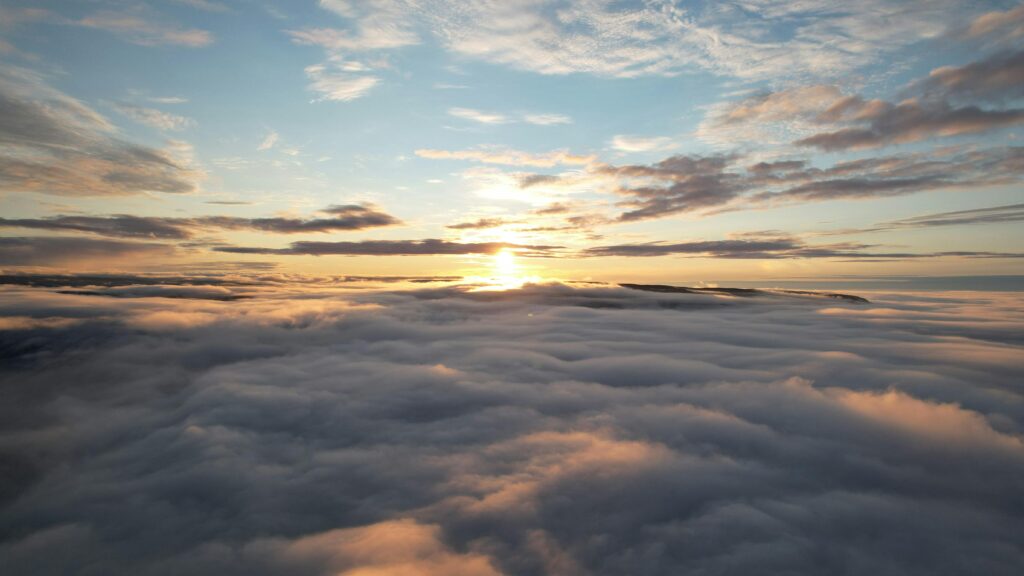 Un paysage apaisant propice à la contemplation montrant un coucher de soleil au dessus d'une mer de nuages