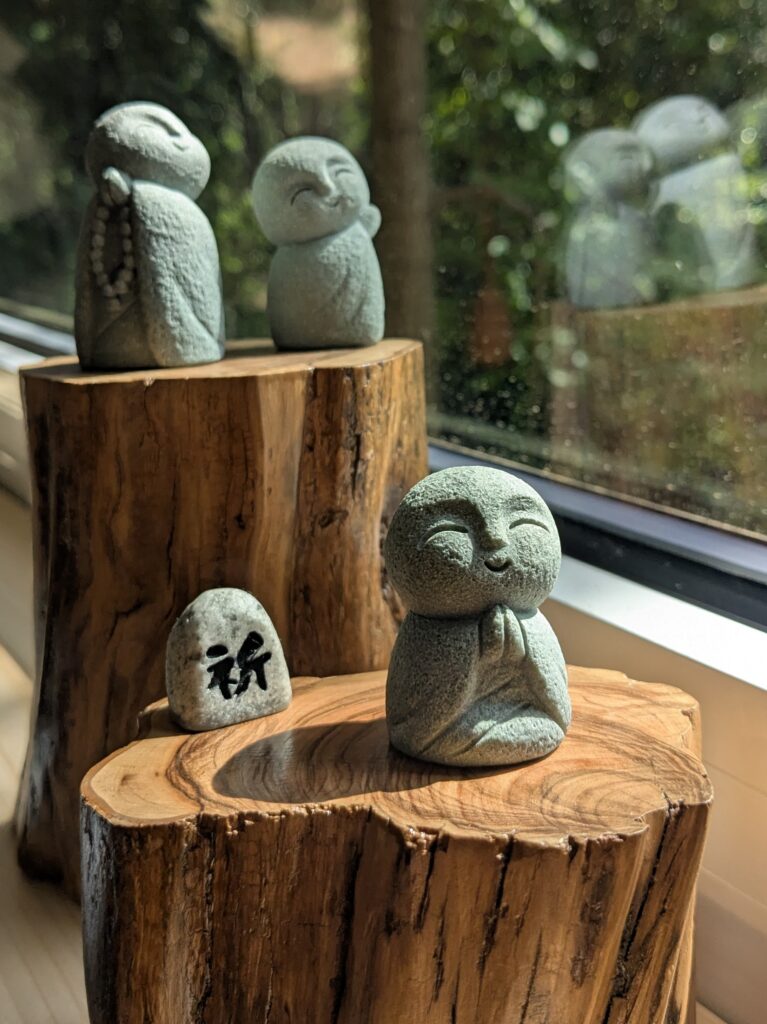 trois petits jizo Bodhisattva protecteur japonais méditent au soleil sur des supports en bois d'olivier